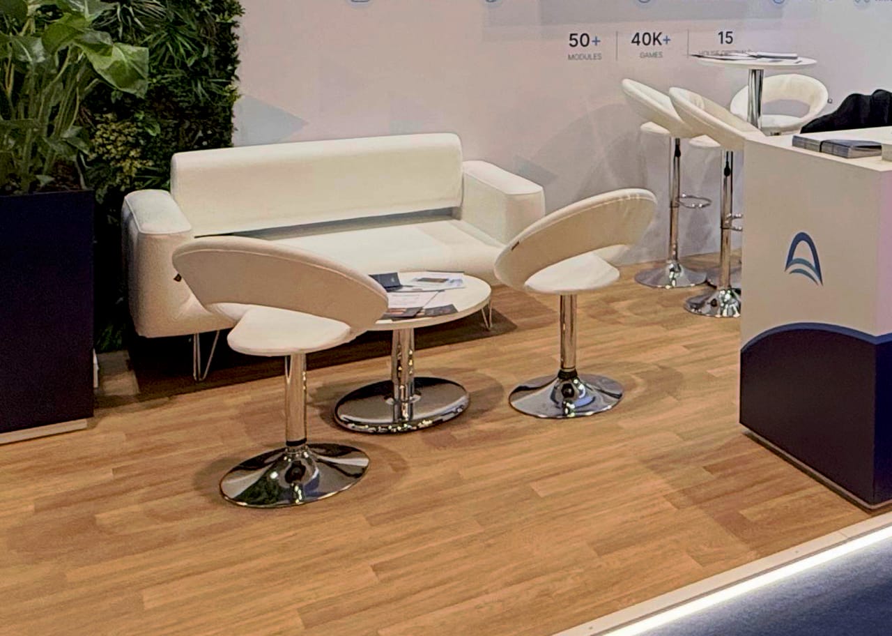 White lounge seating on the wooden floor of the GameBridge stand